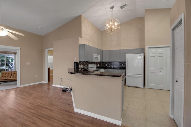 kitchen with light hardwood / wood-style flooring, kitchen peninsula, decorative light fixtures, white appliances, and gray cabinets