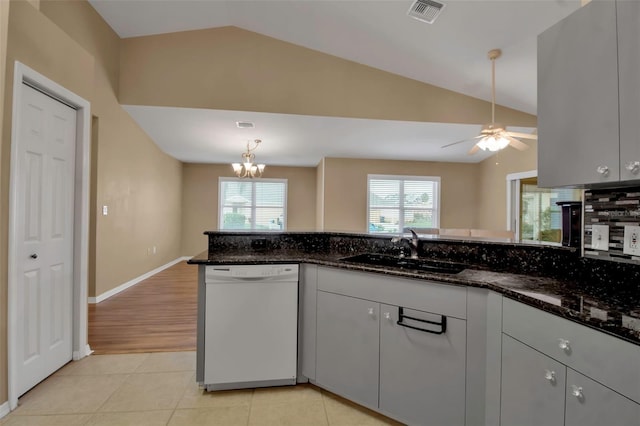 kitchen featuring dishwasher, light tile patterned floors, vaulted ceiling, and dark stone counters