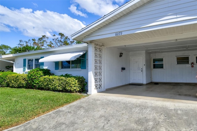 doorway to property with a yard and a carport