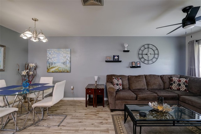 living room with light hardwood / wood-style floors and ceiling fan with notable chandelier