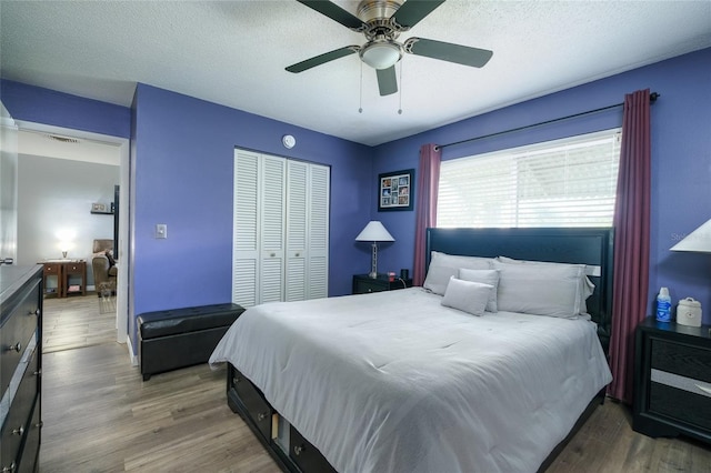 bedroom featuring hardwood / wood-style flooring, ceiling fan, a textured ceiling, and a closet