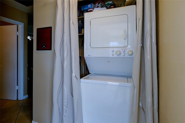 laundry area with stacked washer and dryer and dark tile patterned floors