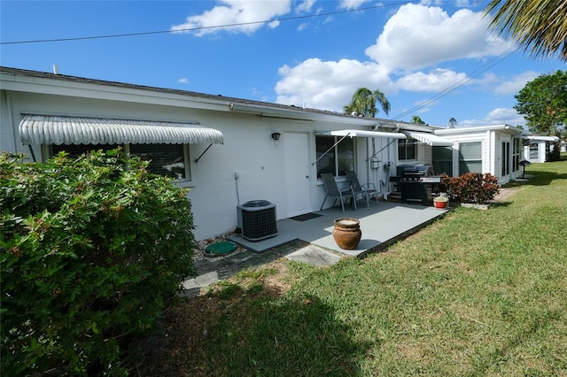 rear view of property with a patio area, a lawn, and cooling unit