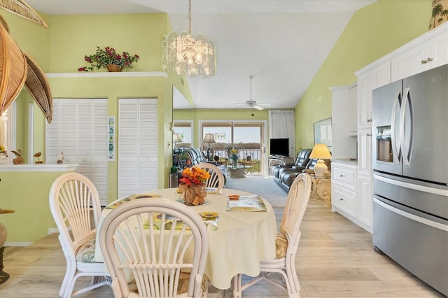 dining space featuring lofted ceiling, ceiling fan with notable chandelier, and light hardwood / wood-style flooring