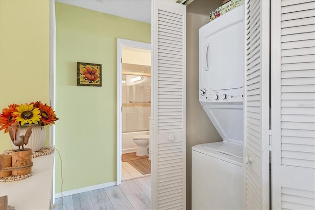 laundry room with stacked washer and clothes dryer and light wood-type flooring