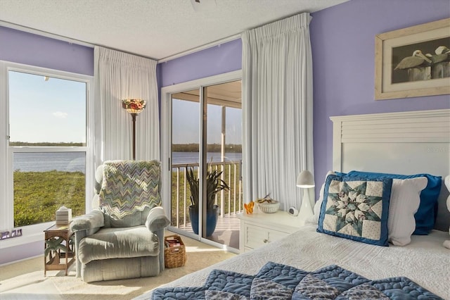 bedroom featuring access to outside, a water view, a textured ceiling, and carpet flooring