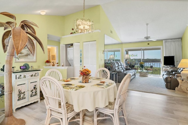 dining room with high vaulted ceiling, ceiling fan with notable chandelier, and light hardwood / wood-style floors