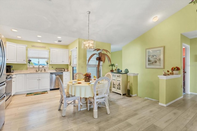 kitchen featuring light hardwood / wood-style floors, stainless steel dishwasher, pendant lighting, sink, and white cabinetry