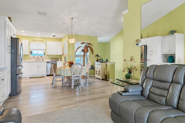 living room featuring sink, a notable chandelier, and light wood-type flooring