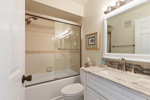 full bathroom featuring toilet, bath / shower combo with glass door, and vanity