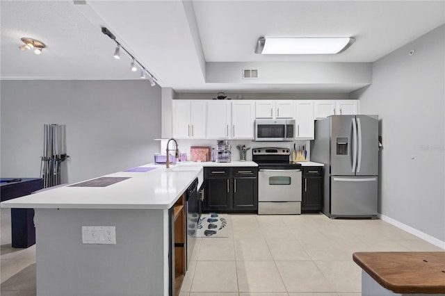 kitchen featuring appliances with stainless steel finishes, light tile patterned floors, white cabinets, sink, and rail lighting