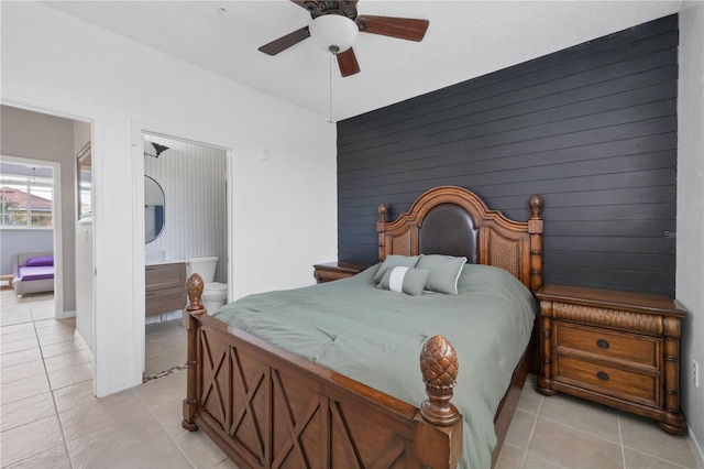 bedroom with ceiling fan, wooden walls, and light tile patterned floors