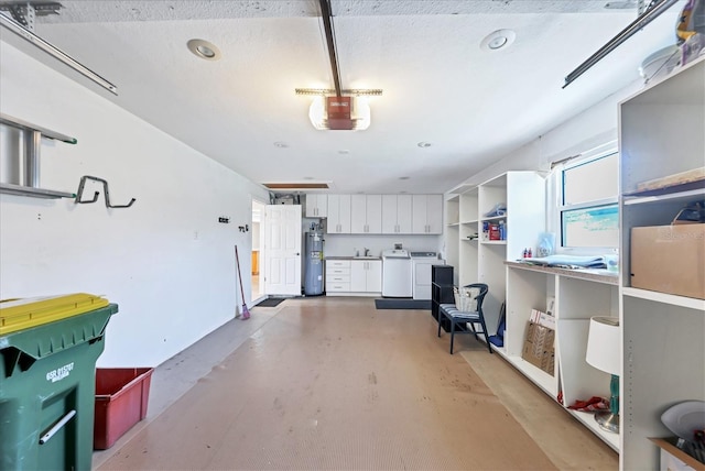 garage with washing machine and clothes dryer, water heater, and sink