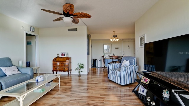 living room with ceiling fan with notable chandelier and hardwood / wood-style flooring