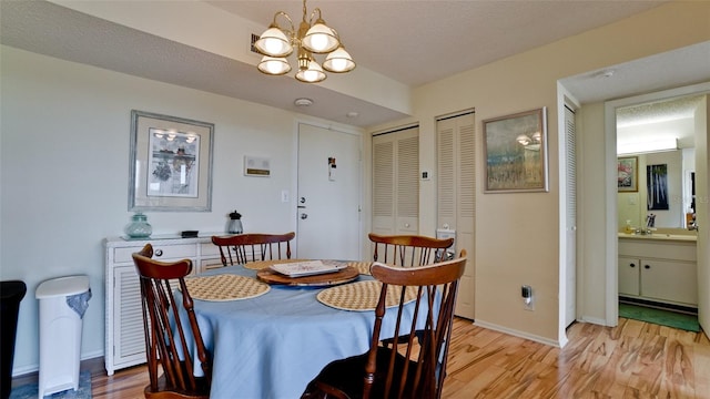 dining space featuring an inviting chandelier, a textured ceiling, and light wood-type flooring