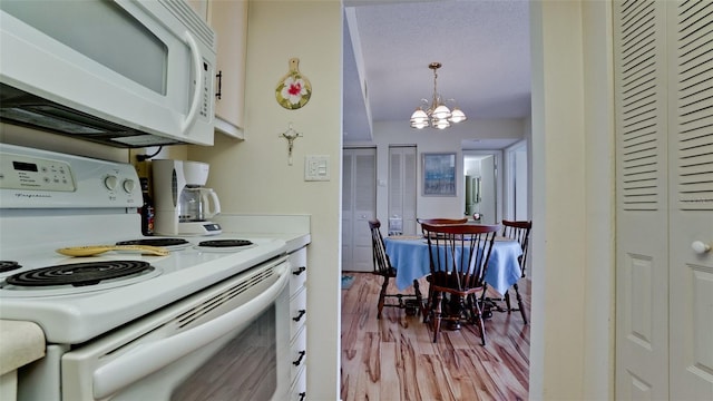 kitchen featuring white cabinetry, white appliances, a chandelier, light hardwood / wood-style flooring, and pendant lighting