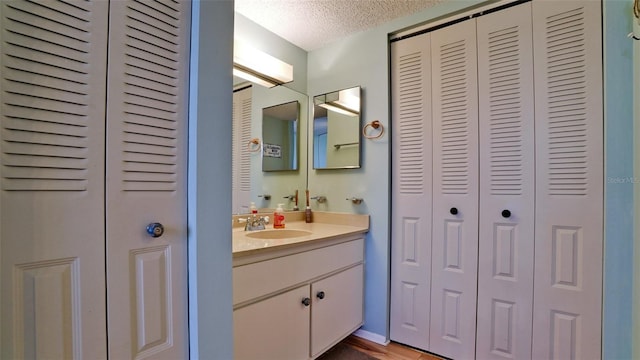 bathroom with hardwood / wood-style floors, vanity, and a textured ceiling