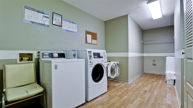 washroom with light hardwood / wood-style flooring and washing machine and clothes dryer