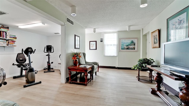 workout room featuring a textured ceiling and light hardwood / wood-style floors