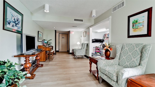 living area featuring a textured ceiling and light hardwood / wood-style floors