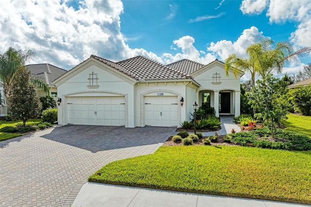 mediterranean / spanish home featuring a front yard and a garage