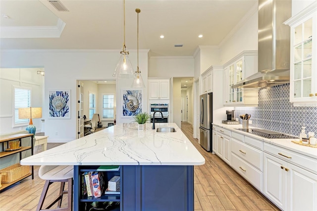 kitchen with white cabinetry, a spacious island, wall chimney exhaust hood, light hardwood / wood-style floors, and stainless steel refrigerator