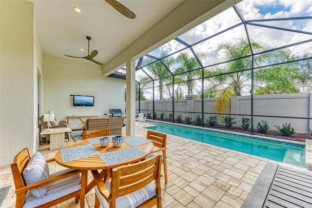 view of swimming pool featuring glass enclosure, ceiling fan, a patio, and an outdoor living space