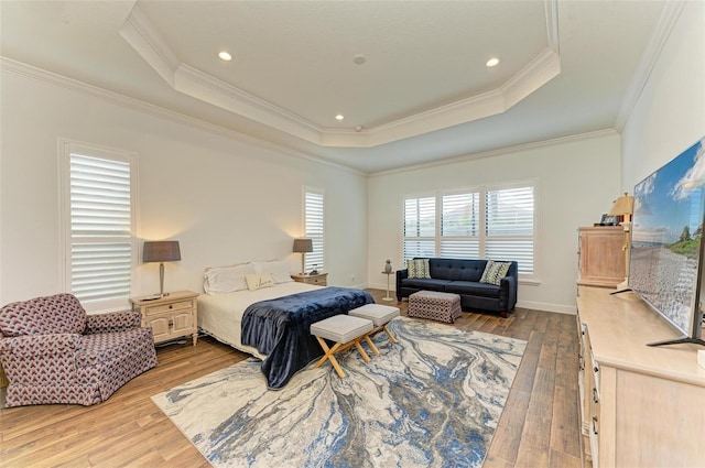 bedroom with a tray ceiling, light hardwood / wood-style flooring, and crown molding