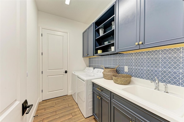 washroom featuring separate washer and dryer, sink, cabinets, and light hardwood / wood-style floors