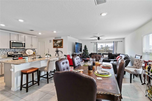 tiled dining area featuring ceiling fan, sink, and a textured ceiling