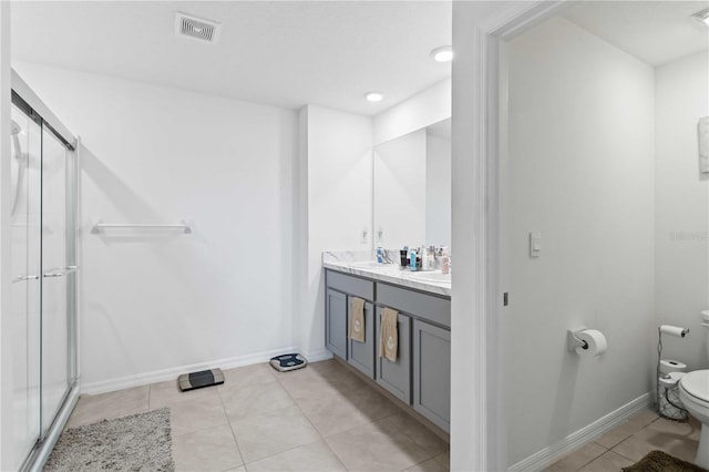 bathroom featuring tile patterned flooring, vanity, a shower with door, and toilet