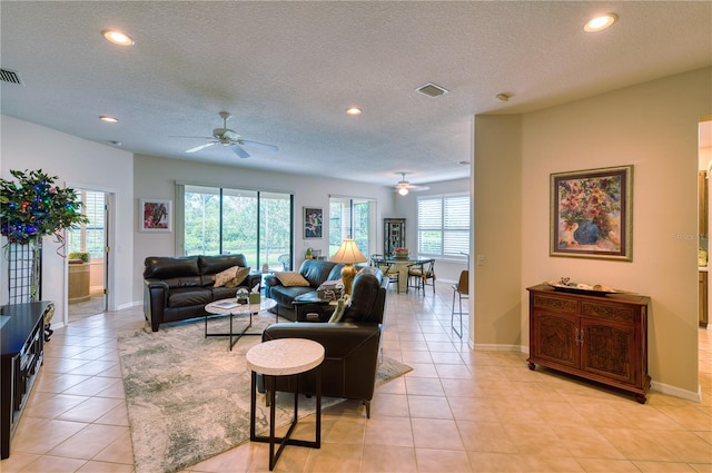 tiled living room featuring a textured ceiling, ceiling fan, and a healthy amount of sunlight