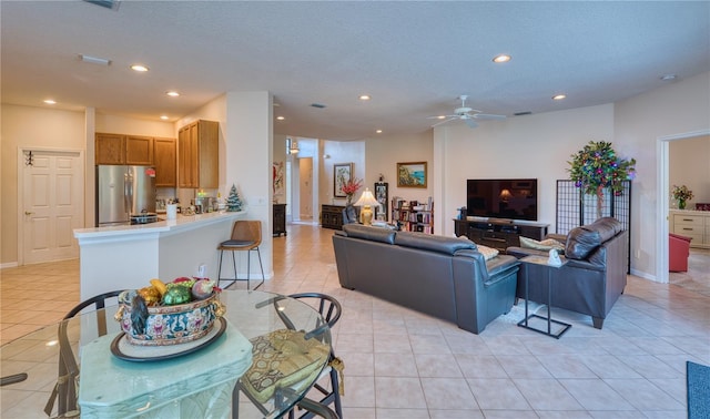 living room with ceiling fan, light tile patterned floors, and a textured ceiling