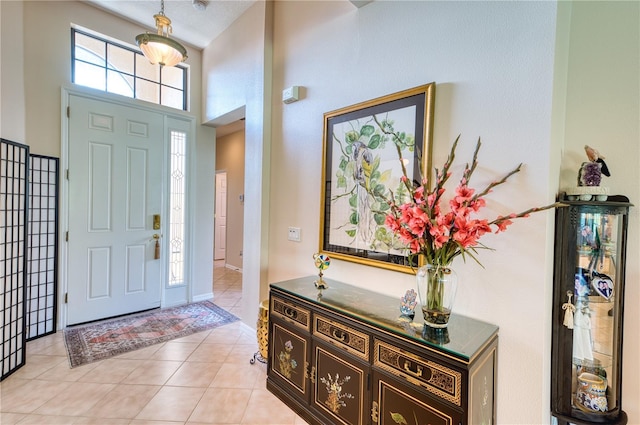 entryway featuring a high ceiling, a textured ceiling, and light tile patterned flooring