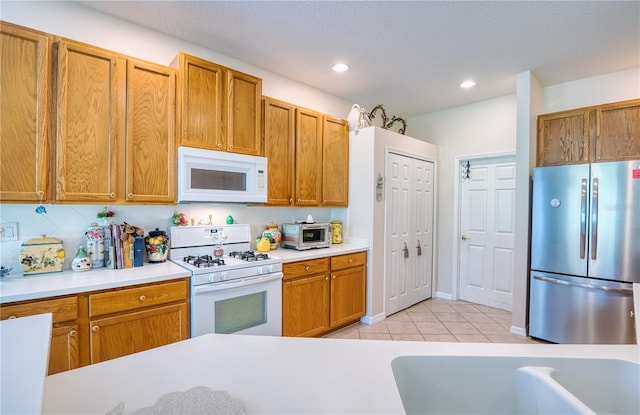 kitchen with backsplash, a textured ceiling, light tile patterned floors, and white appliances