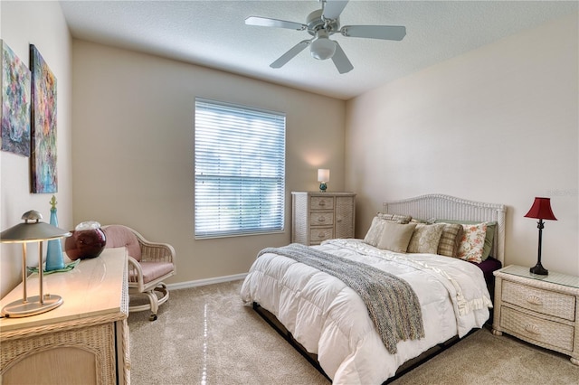 bedroom with ceiling fan, light carpet, and a textured ceiling