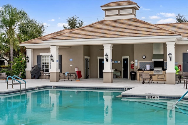 view of swimming pool with a patio, a grill, and an outdoor kitchen