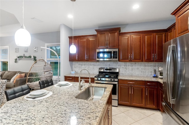 kitchen with sink, stainless steel appliances, decorative light fixtures, and a wealth of natural light