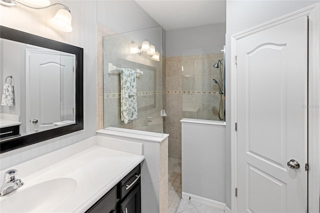 bathroom featuring tile patterned floors, tiled shower, and vanity