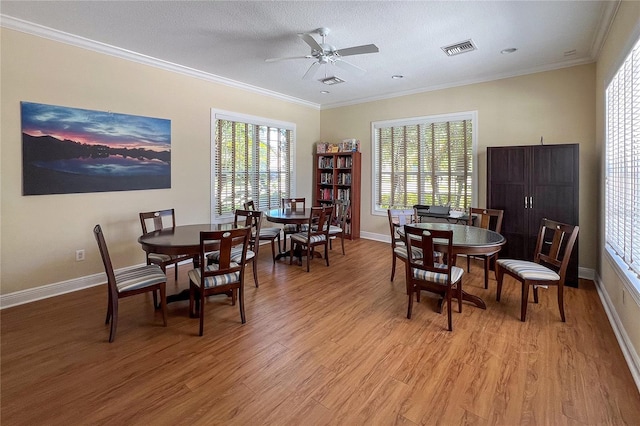 dining room with ceiling fan, light wood-type flooring, crown molding, and plenty of natural light