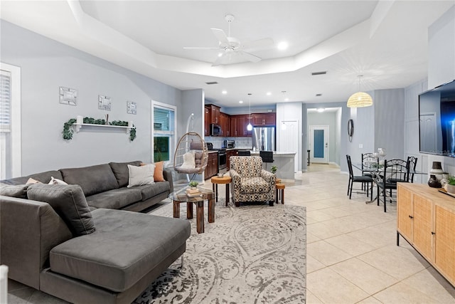 tiled living room featuring a raised ceiling and ceiling fan