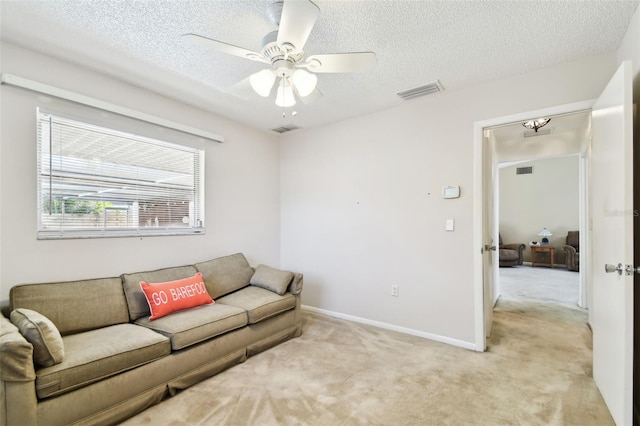 living room featuring ceiling fan, light colored carpet, and a textured ceiling