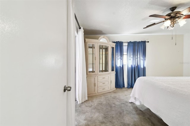 bedroom featuring a textured ceiling, ceiling fan, and light carpet