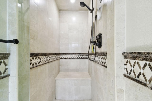 bathroom with a tile shower and tile walls