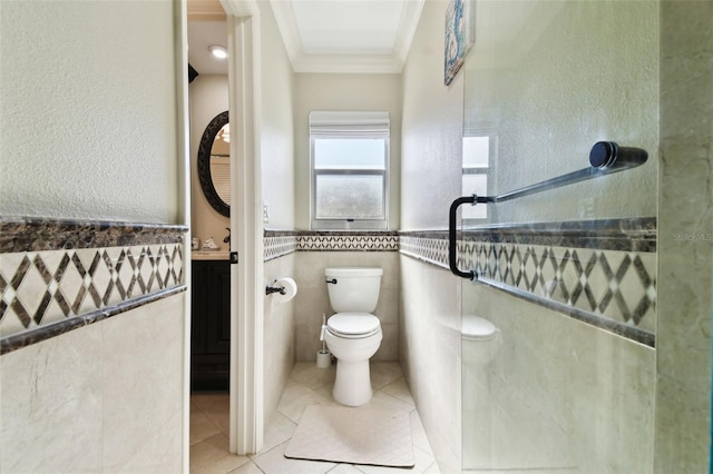 bathroom featuring tile patterned floors, crown molding, a shower, toilet, and tile walls