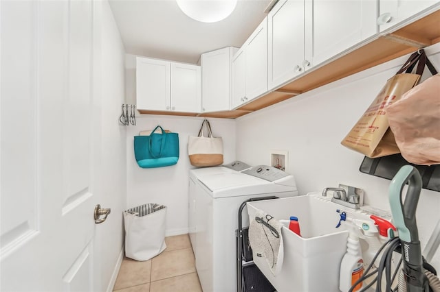 laundry room with cabinets, light tile patterned floors, washing machine and dryer, and sink