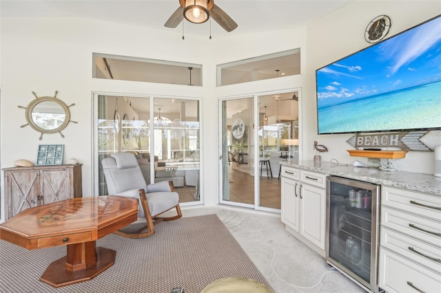 kitchen featuring white cabinetry, light stone countertops, ceiling fan, wine cooler, and light colored carpet