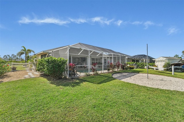 rear view of property featuring a yard and glass enclosure