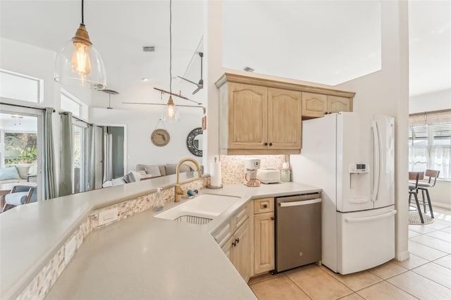 kitchen featuring white fridge with ice dispenser, sink, stainless steel dishwasher, pendant lighting, and light brown cabinetry