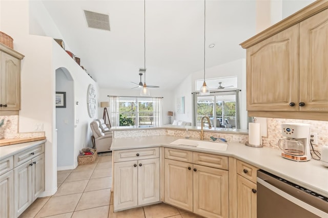 kitchen featuring decorative backsplash, stainless steel dishwasher, sink, light brown cabinets, and decorative light fixtures